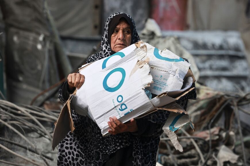 With fuel and other essentials scarce, a  woman carries cardboard boxes to help make a fire in Rafah, the southern Gaza Strip