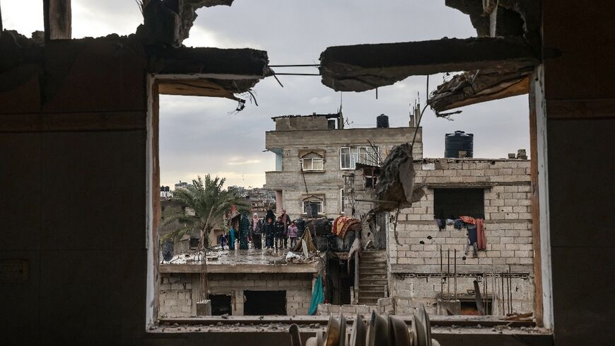 A family stands on a rooftop opposite a building damaged by Israeli bombing in Rafah in the southern Gaza Strip