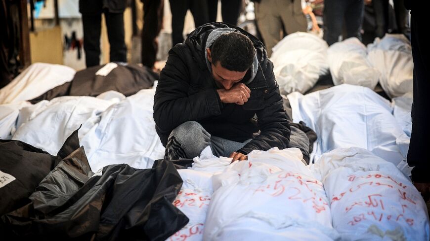 A Palestinian man mourns over shrouded bodies of relatives killed in overnight Israeli bombardment on the southern Gaza Strip at Al-Najjar hospital in Rafah on February 8, 2024